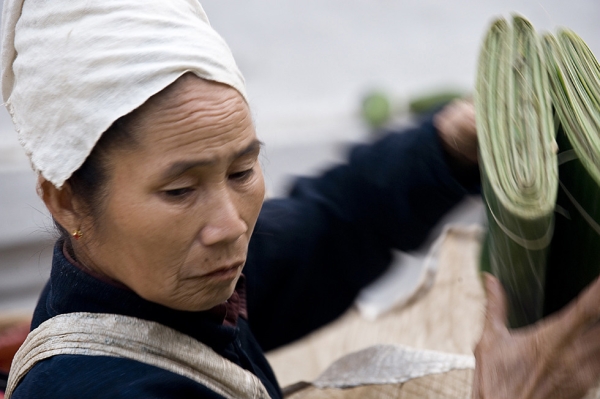 A Laotian woman in Luang Prabang protects her head from the heat as she organizes her banana leaves to sell them in a street market on April 10, 2009. (Nancy A. Scherl)