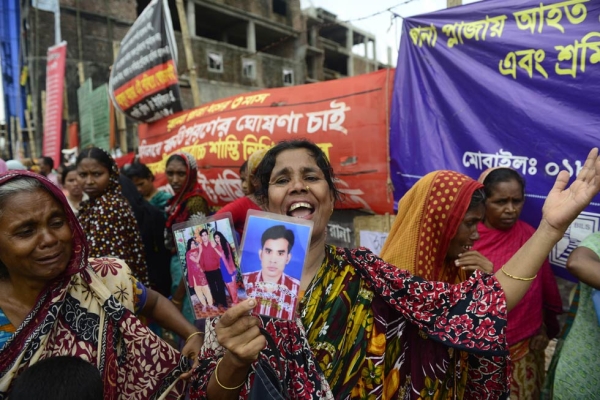 A mourner holds pictures of a relative lost in the collapse of Rana Plaza in Bangladesh on April 24, 2013, considered the deadliest accidental structural failure in human history. (Munir Uz Zaman/AFP/Getty Images)