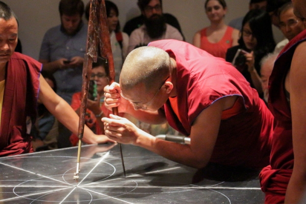 The monks begin by drawing an outline of the mandala on the wooden platform. (Nikki Tripp)