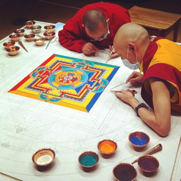 The monks began by drawing a formal pattern on the base and are now placing millions of grains of brightly colored sand to complete the mandala. (Dan Washburn)