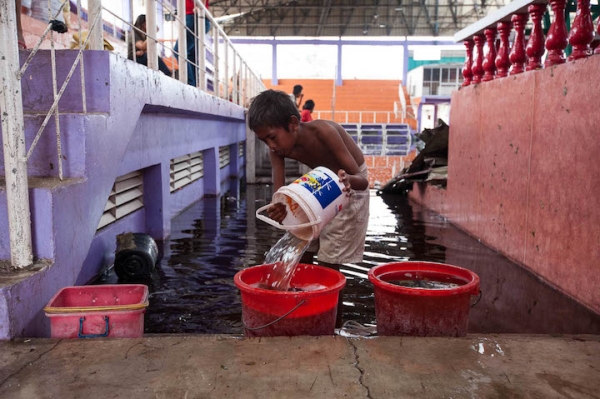 A child scoops water out of the flooded sports complex in Medellin, Bogo in the aftermath of Typhoon Yolanda.
