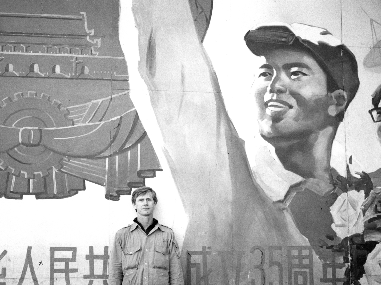 Orville Schell stands under a propaganda billboard in Qingdao, China, in 1981.