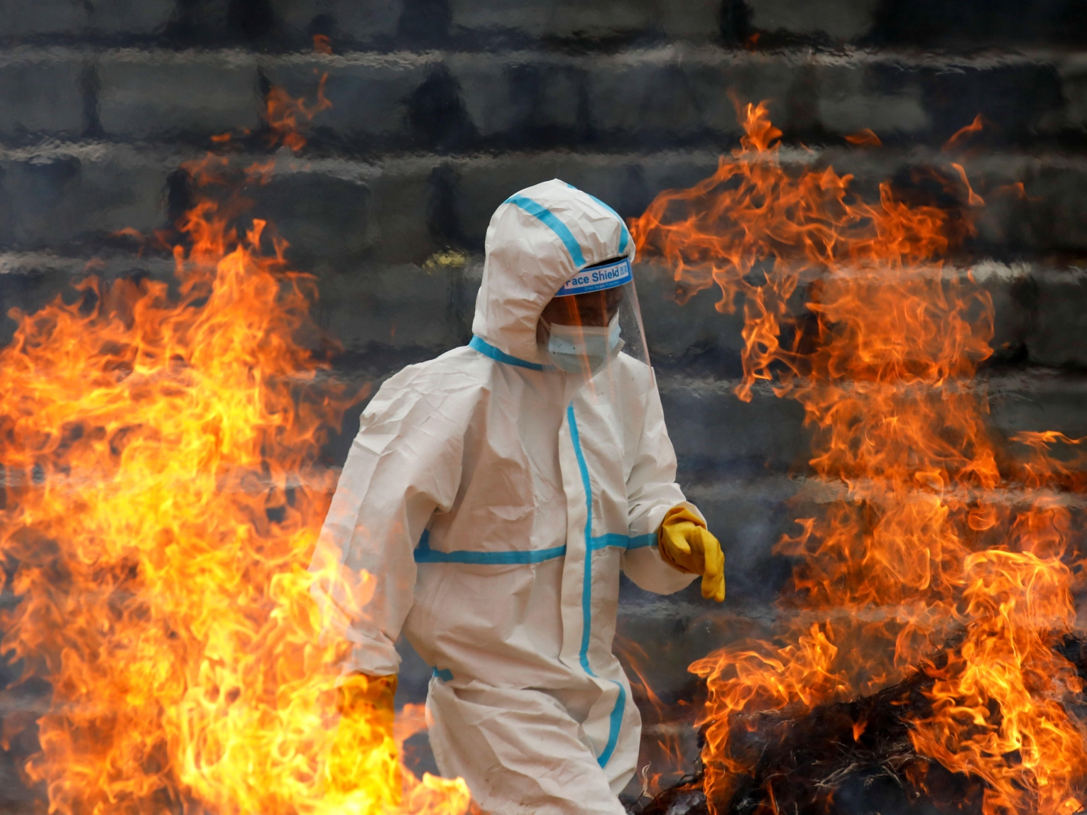 A man wearing personal protective equipment helps cremate the bodies of COVID-19 victims.
