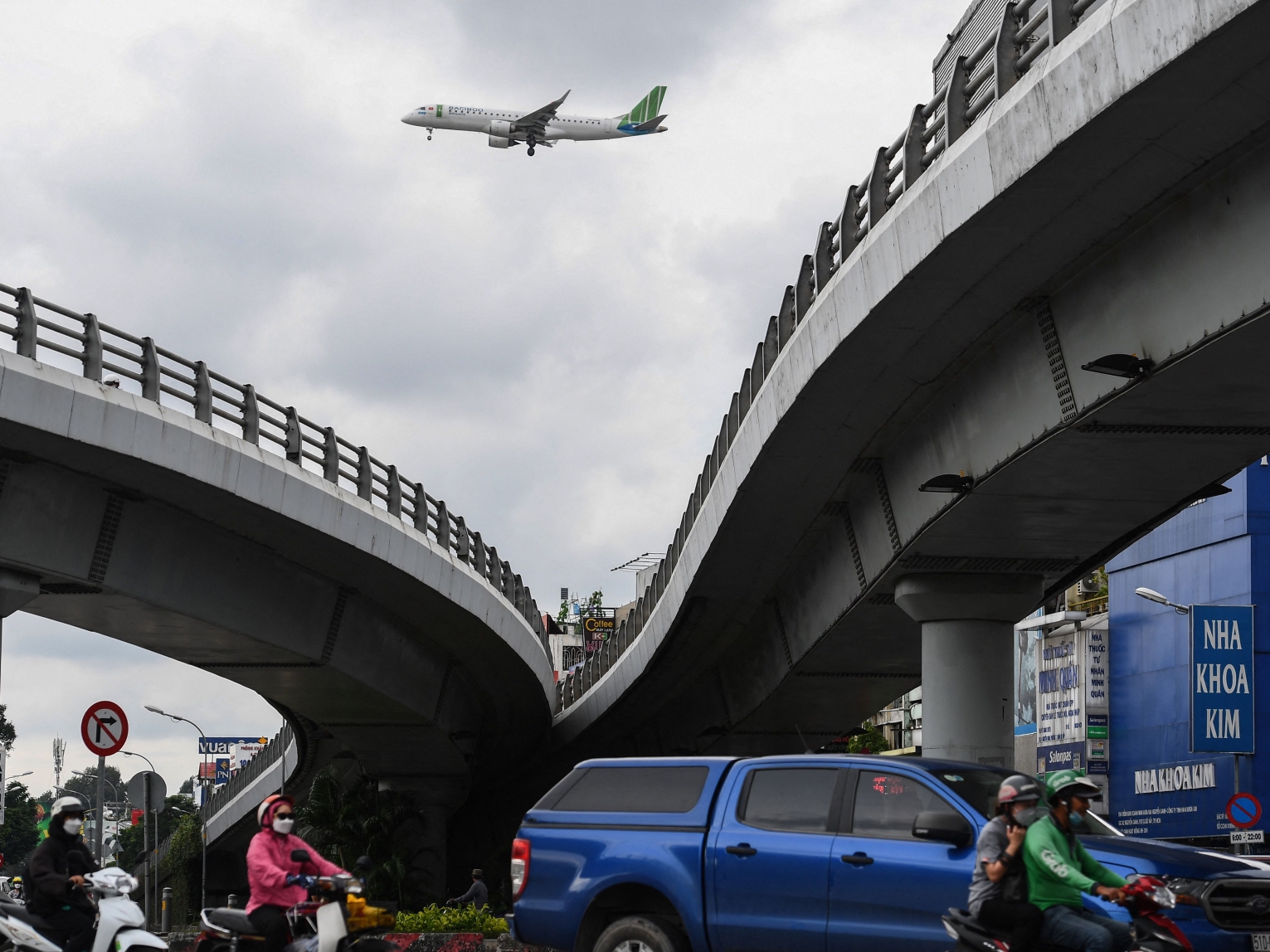 An airplane flies over commuters on a street in Ho Chi Minh City on September 22, 2022. Tan Son Nhat International Airport has been operating well over capacity for years, but efforts to build a third terminal have been slowed due, in part, to what analysts say are unintended consequences of an anti-corruption crackdown. 