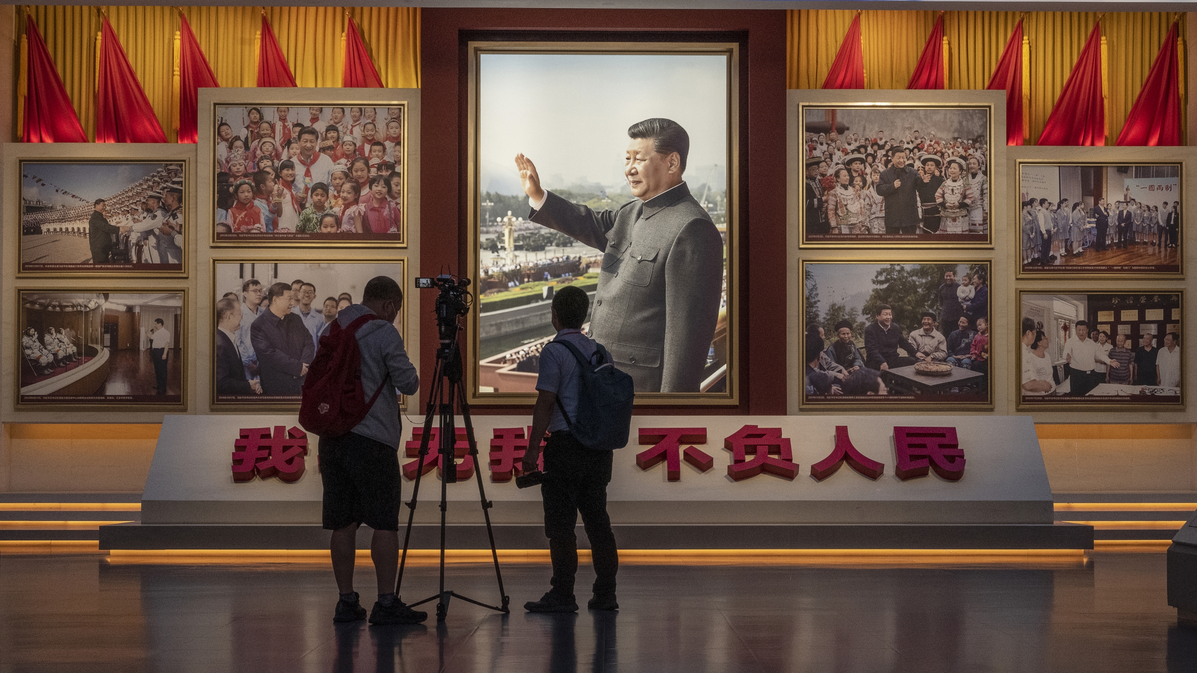 Journalists stand in front of a wall showing images of Communist Party Chairman and President Xi Jinping as part of a display at the newly built Museum of the Communist Party of China on June 25, 2021 in Beijing, China. 