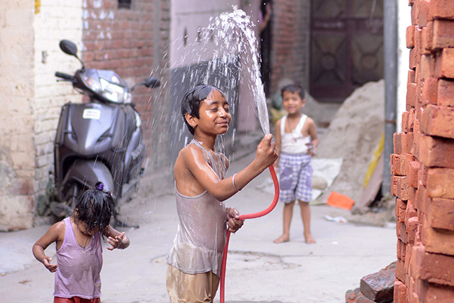 An Indian Boy Washes Himself With Water To Cool D