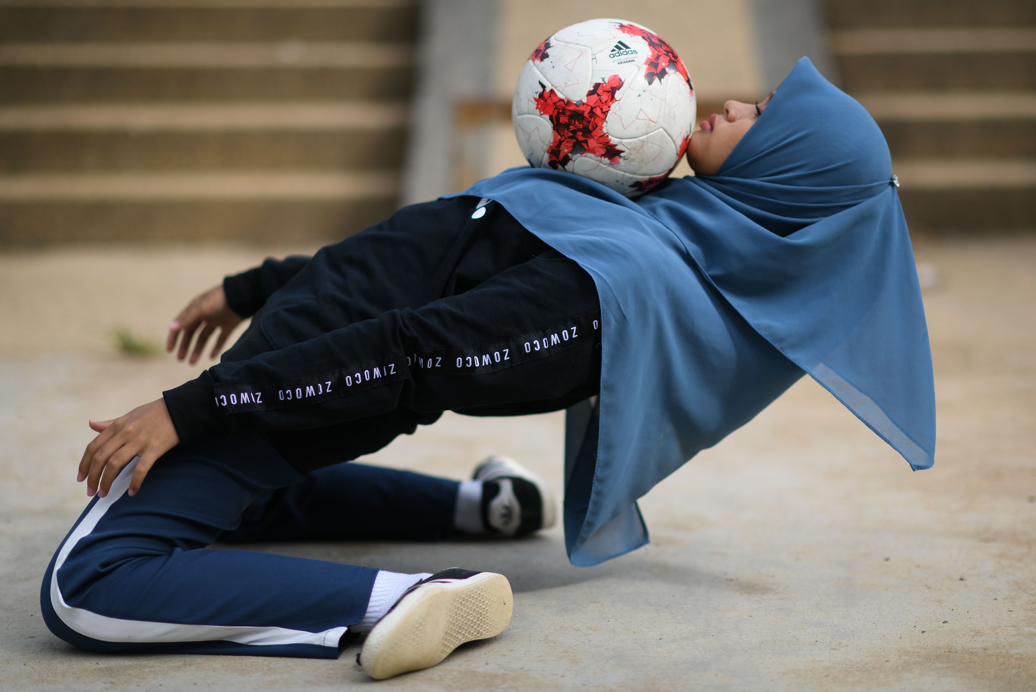 A girl balancing a soccer ball on her body