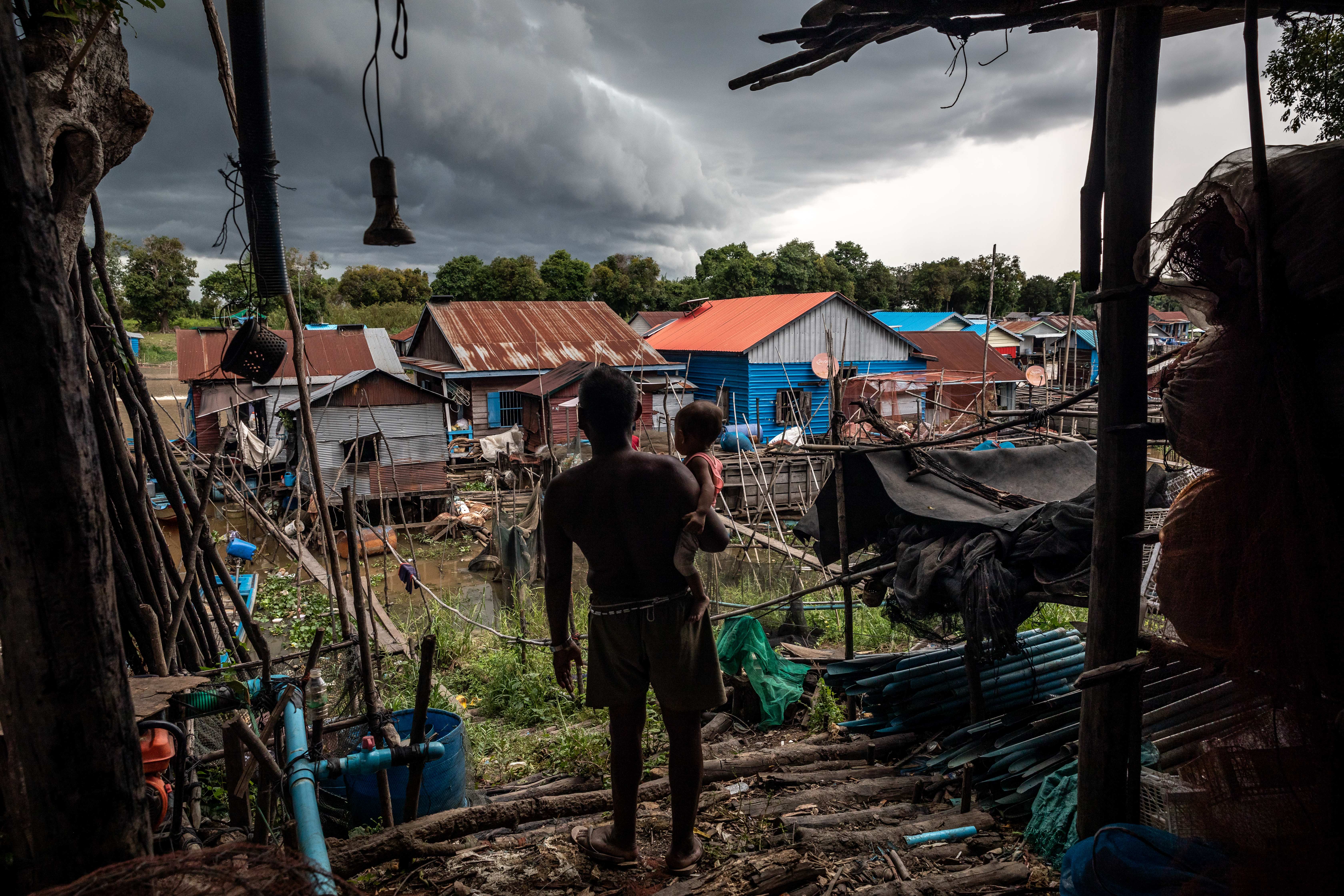 Chim Arn, 59, takes his grandson for a walk in July 2021 to watch the storm over his village in Siem Reap's Por Treay commune. 