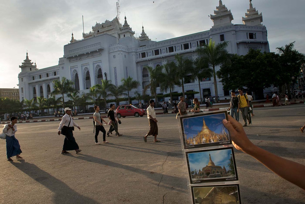 A boy hawks postcards of Myanmar's monuments to a visitor in front of Yangon city hall. (Gilles Sabrié)