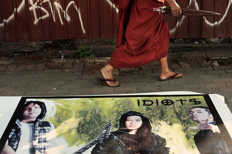 A monk passes by a promotional poster for the local rock band "Idiots." (Gilles Sabrié)
