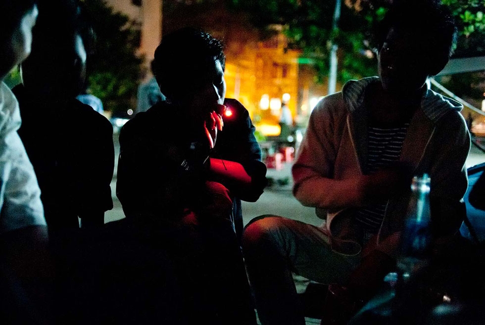In a dimly lit street of Yangon, youth share a joint. The use of weed is very common among Burmese youth. (Gilles Sabrié)