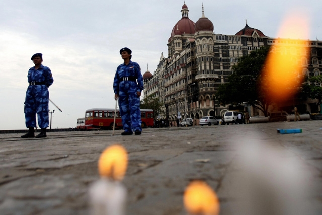 Indian paramilitary forces stand guard as candles placed by people in memory of those killed by militants burn in front of the Taj Mahal hotel in Mumbai on November 30, 2008. (Sajjad Hussain/AFP/Getty Images)  