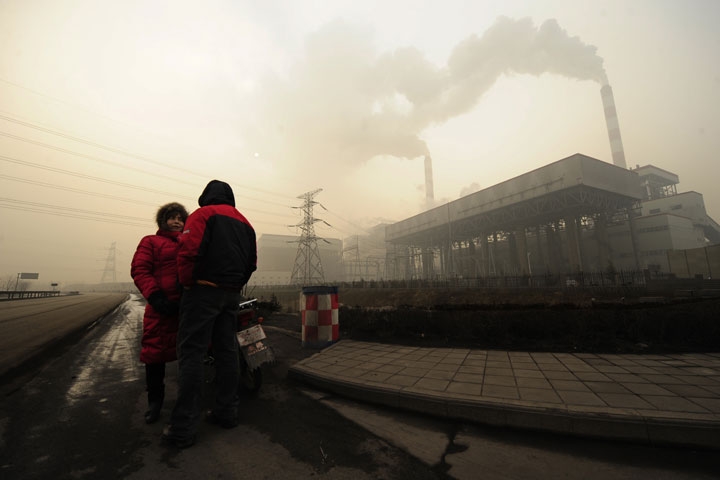 This photo taken on December 8, 2009 shows two people outside a coal-powered power plant on the outskirts of Linfen, China, regarded as one of the cities with the worst air pollution in the world. (Peter Parks/AFP/Getty Images)
