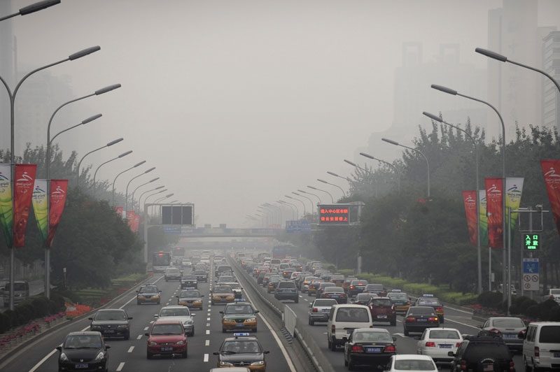 Cars drive through thick smog in Beijing on Sept. 21, 2008, the first day of no traffic restrictions that had limited motorists during the Olympic and Paralympic Games. (Peter Parks/AFP/Getty Images)
