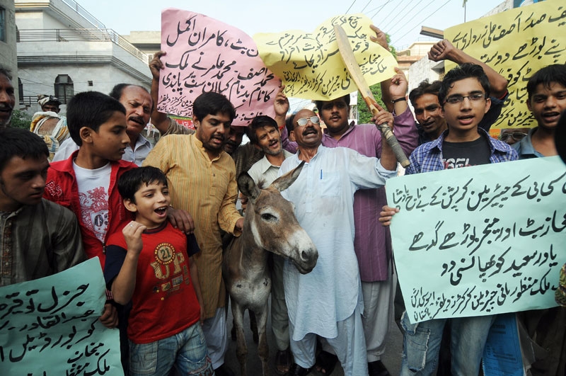 Pakistani cricket fans pose with a donkey as they shout slogans against national cricket team players involved in a match fixing scandal during a protest in Lahore on August 30, 2010. (STR/AFP/Getty Images)