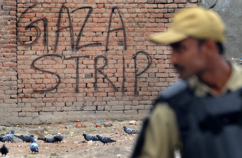An Indian paramilitary trooper stands guard in front of a wall bearing the grafitti 'Gaza Strip' during an undeclared curfew in Srinagar on May 21, 2011. Authorities in restive Indian Kashmir placed separatist leaders under house arrest to thwart a rally marking the anniversaries of the killing of two of the independence movement's key figures. (Rouf Bhat/AFP/Getty Images)