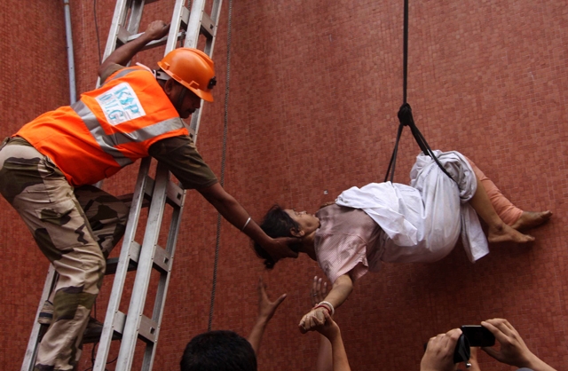 Rescue workers evacuate a woman after a fire engulfed a hospital in the eastern Indian city of Kolkata on December 9, 2011. (Strdel/AFP/Getty Images)