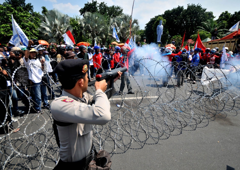 An Indonesian policeman shoots tear gas towards protesters during a protest against the government's plan to hike prices of fuel in Surabaya on March 29, 2012. (STR/AFP/Getty Images)