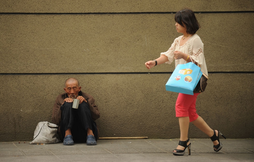 A man begs on a street as a woman passes by in Shanghai on May 9, 2012. China could face an economic crisis in the next 20 years if it does not quickly overhaul its development model, World Bank and Chinese government researchers warned recently. (Peter Parks/AFP/GettyImages)