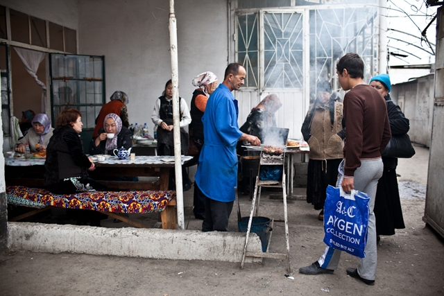 A Kyrgyz cook grills shashlik in a cafe in Osh Bazaar, where customers relax over tea and snacks. (Sue Anne Tay)