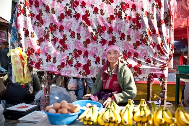 A woman trader sits in front of her fruit stand. (Sue Anne Tay)