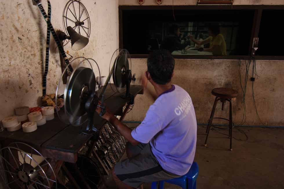 The projectionist rewinds a reel of film by hand at the Thai Rama Theater in Uthumphon Pisai District, Sri Saket, Thailand. (Philip Jablon)