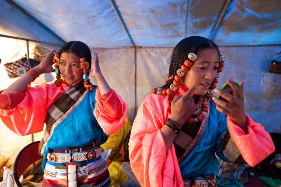 Young women in typically colorful Tibetan costumes primp before their upcoming traditional dance performance at the festival. (Michael Yamashita)