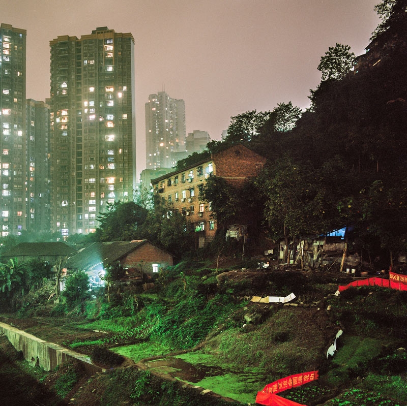 In the Shapingba district, a house and surrounding gardens are lit by urban light pollution as skyscrapers loom large from a nearby housing development project that are gaining most of the lands in this part of town. (Tim Franco)