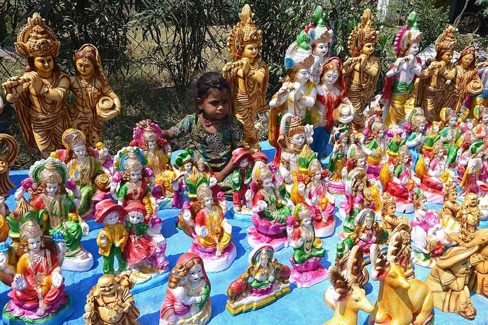 An Indian child, the daughter of a roadside vendor, sits among statues of Hindu Goddess Lakshmi, who represents wealth, at a stall ahead of Diwali in Hyderabad on October 21, 2014. (Noah Seelam/AFP/Getty Images)