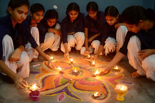 Indian schoolgirls light candles as they sit near a rangoli (a decorative design with sacred overtones) made out of colored powder during a pre-Diwali celebration at a school in Amritsar on November 12, 2012. (Narinder Nanu/AFP/Getty Images)