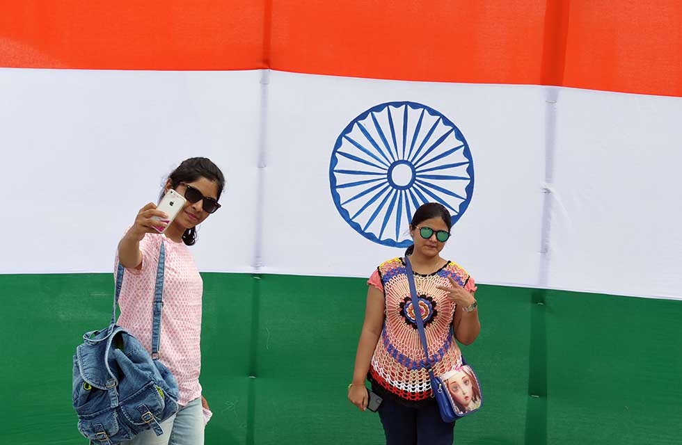 Indian women take a selfie in front of a large national flag at Sudha Cars Museum in Hyderabad, on August 14, 2017. (Noah Seelam/AFP/Getty)