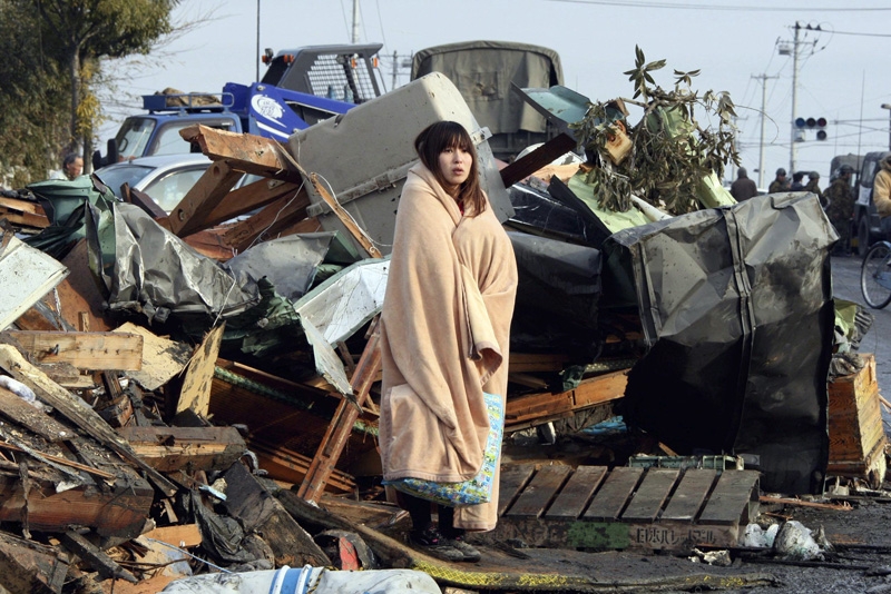  A survivor wrapped in a blanket stands to look on tsunami-damaged town at Ishinomaki city in Miyagi prefecture on March 13, 2011. (Yomiuri Shimbun /AFP/Getty Images) 