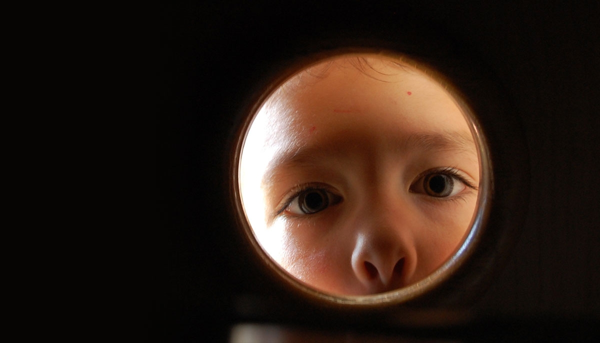 A child looks through a small window or opening. (Caritas5/Flickr)