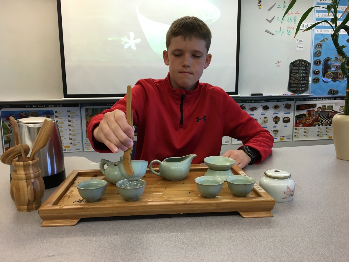 A middle school student demonstrates a tea ceremony to his class.