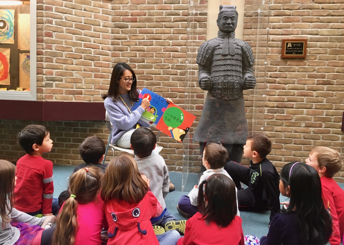 A teacher reads to her immersion students next to a life-size replica of a Terracotta warrior.