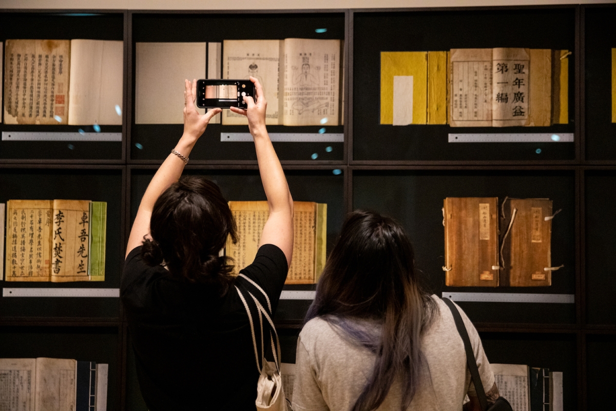 Friends snap a picture of Xiaoze Xie’s “Scrutiny (Premodern Books),” on display as part of Asia Society Museum’s exhibition "Xiaoze Xie: Objects of Evidence."