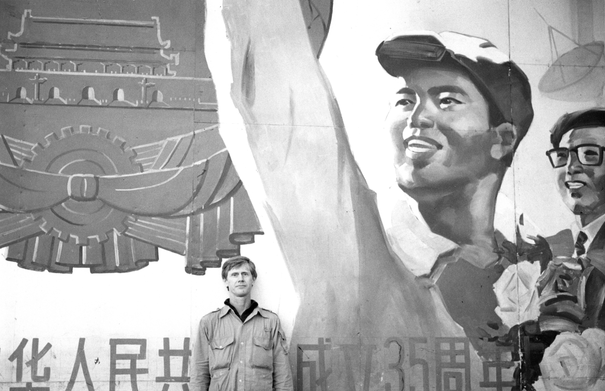 Orville Schell stands under a propaganda billboard in Qingdao, China, in 1981.