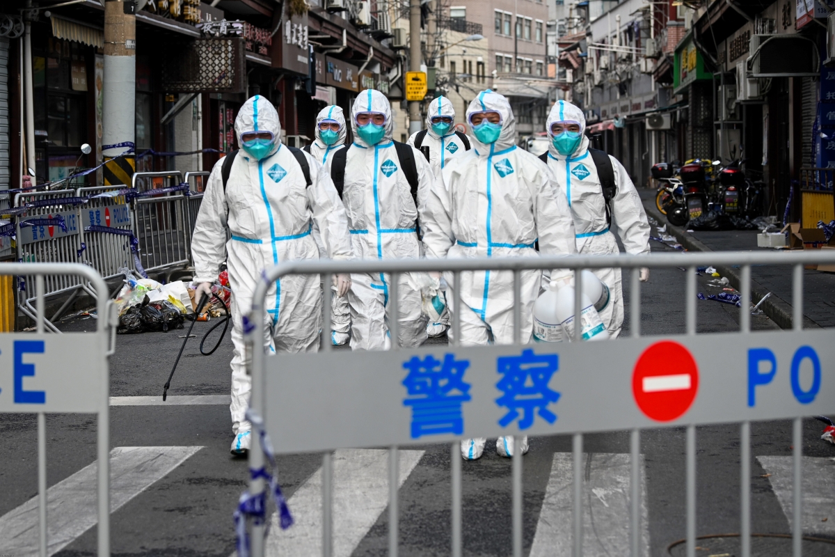 Health workers in protective gear walk out from a blocked off area after spraying disinfectant in Shanghai's Huangpu district on January 27, 2021, after residents were evacuated following the detection of a few cases of COVID-19 coronavirus in the neighbourhood.