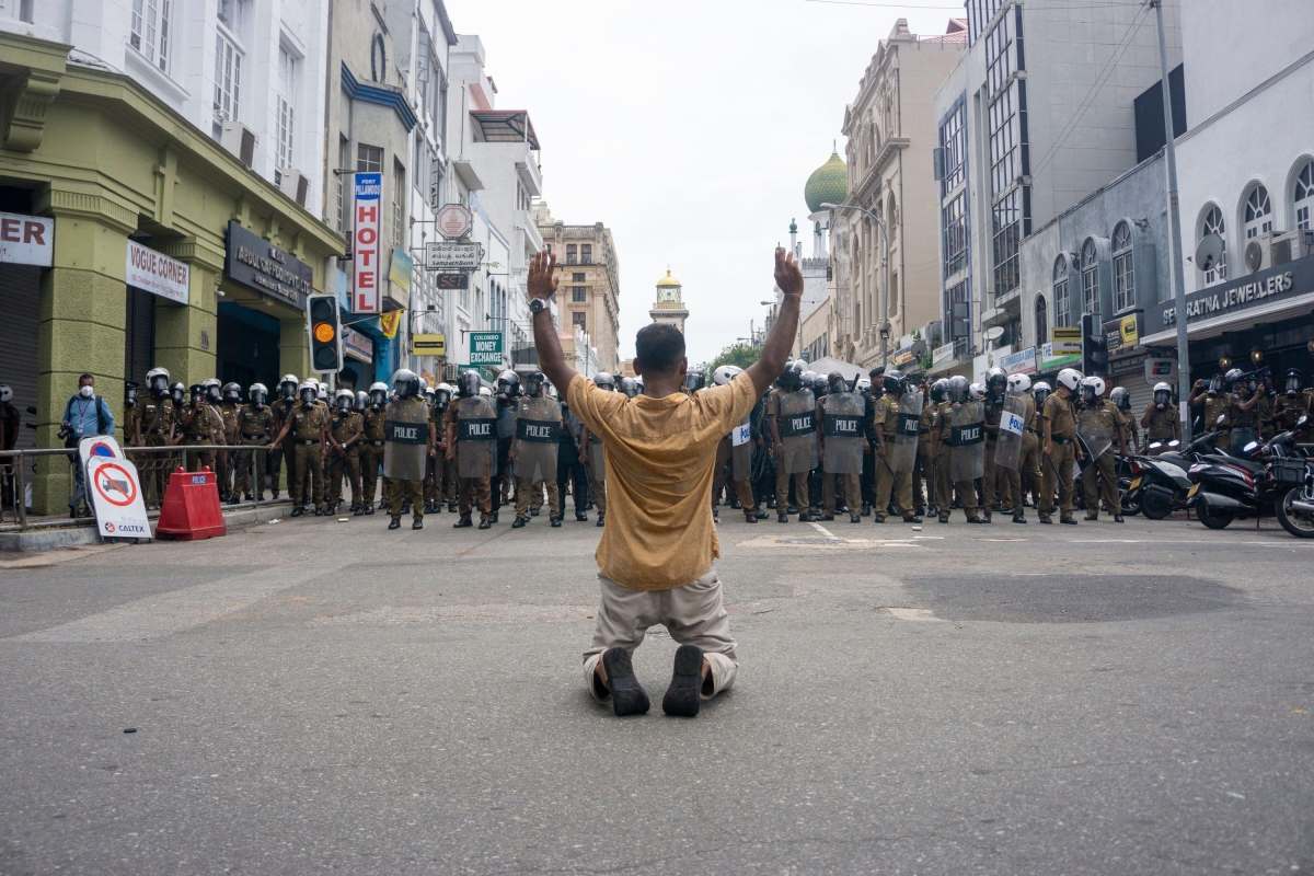 A man kneels before police during a protest held by a group of farmers near the presidential palace in Colombo, Sri Lanka on July 6, 2022.