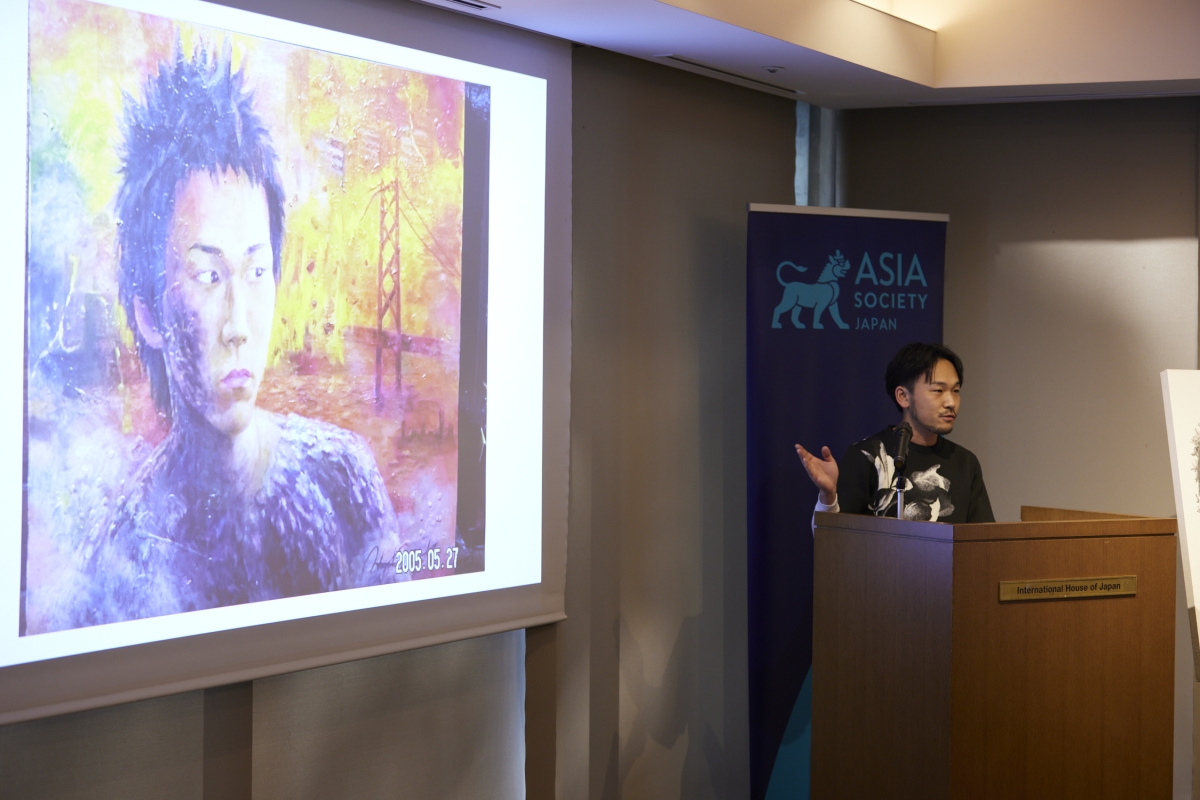 Nishigaki giving a presentation showing his portrait painting on screen