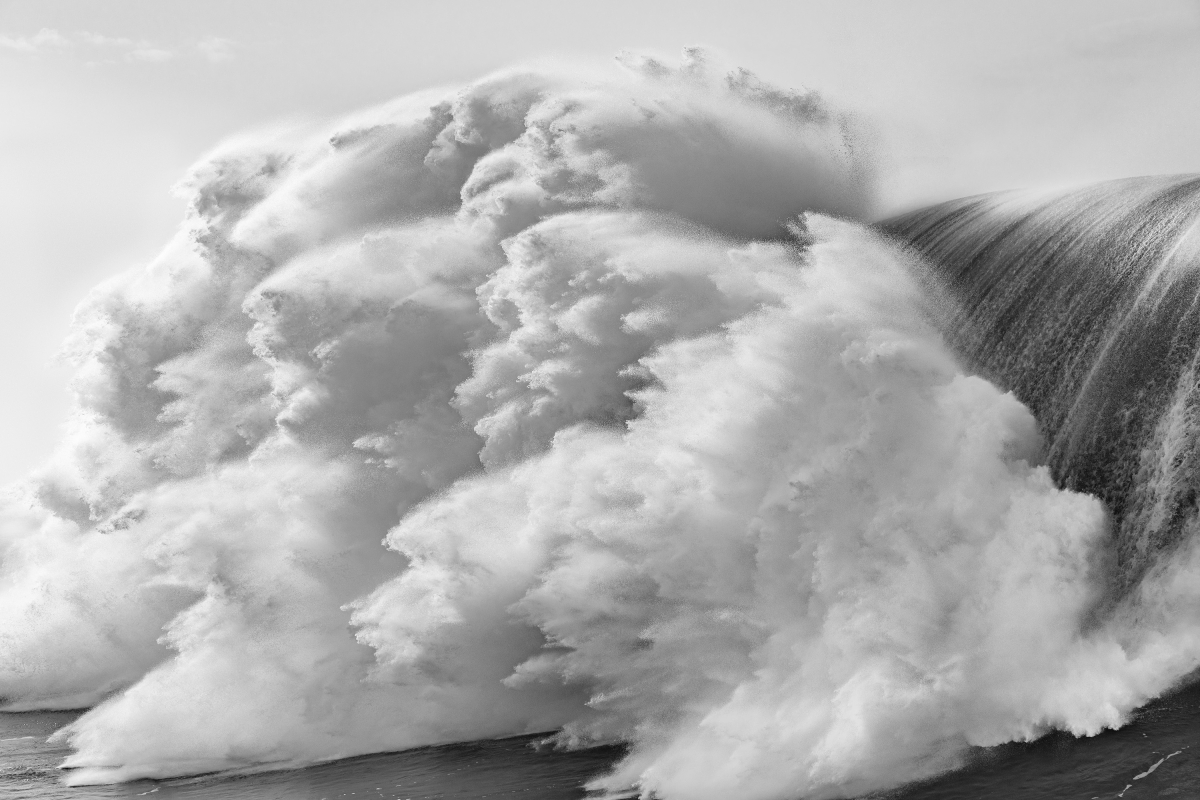 Black-and-white photograph of a large breaking wave.