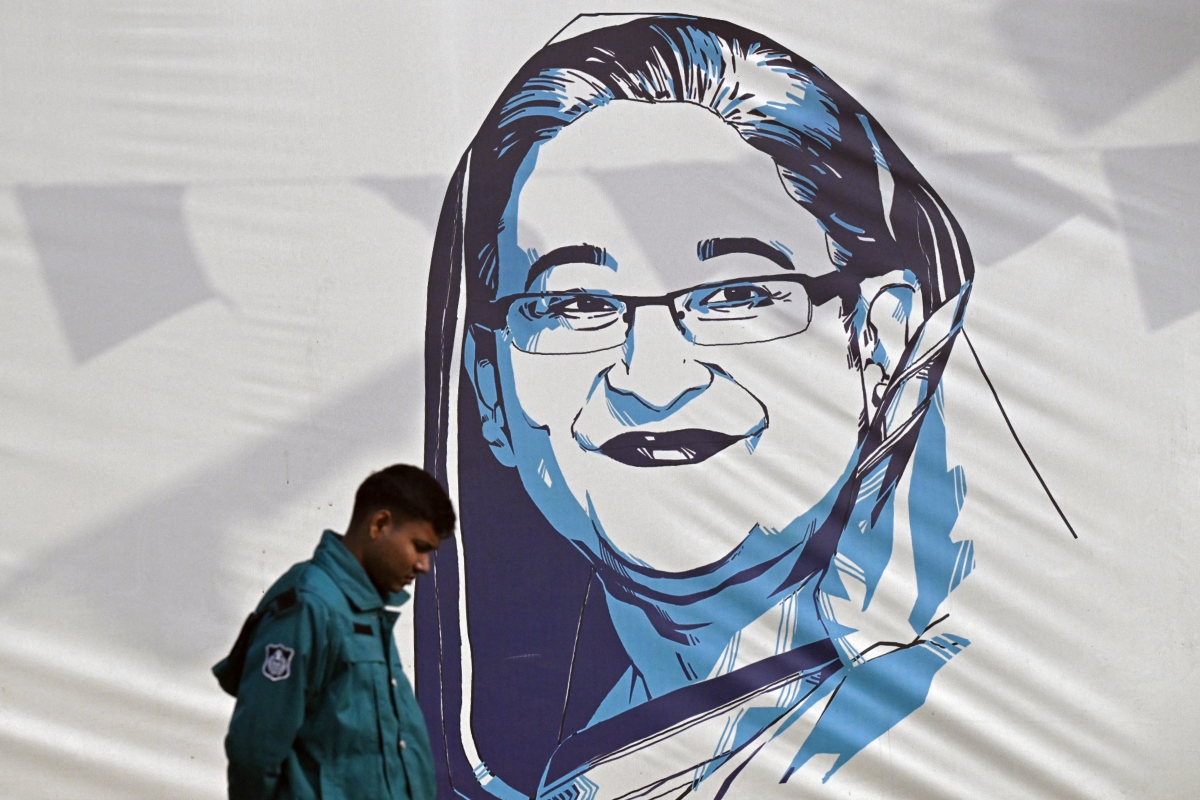  policeman walks past a portrait of Bangladesh's Prime Minister Sheikh Hasina, in Dhaka on January 8, 2024. Hasina won re-election for a fifth term on January 7, officials said, following a boycott led by an opposition party she branded a "terrorist organisation".