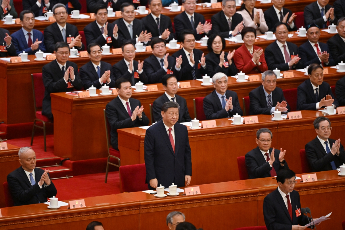 China's President Xi Jinping is applauded by Premier Li Qiang, Politburo Standing Committee member Cai Qi