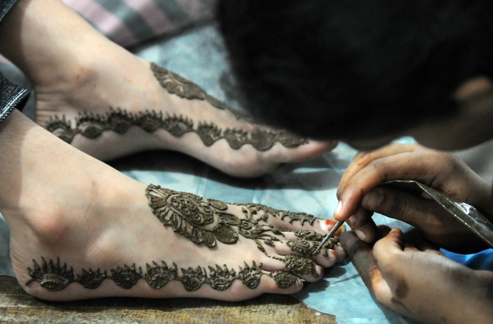 A Karachi beautician applies traditional henna designs to the foot of a customer at a beauty salon ahead of Eid-ul-Fitr in 2009. (Asif Hassan/AFP/Getty Images)