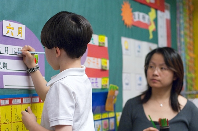 In 1st grade Mandarin Immersion a selected student fills in the daily calendar. 