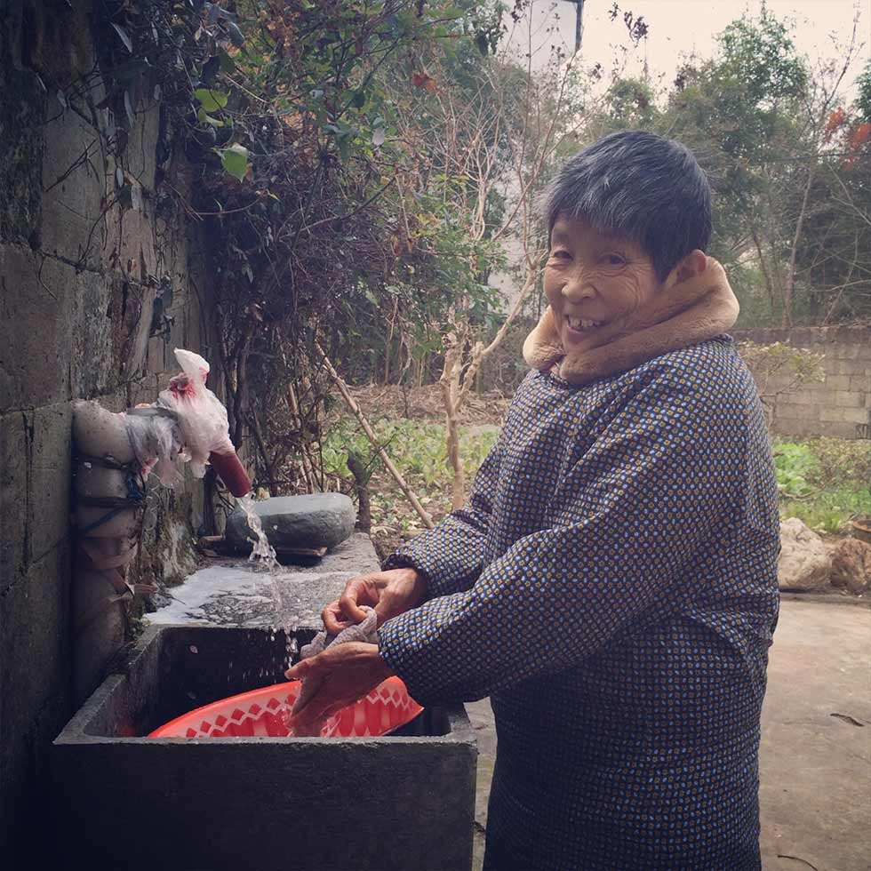 Shu Juzhen washing cloth in her backyard. (Sun Yunfan)