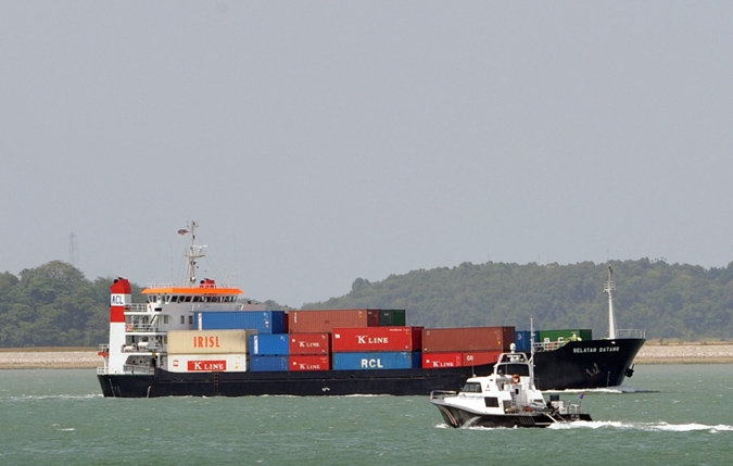 A vessel loaded with containers sails past a maritime coast guard on patrol along the Singapore Straits on February 20, 2008. (ROSLAN RAHMAN/AFP/Getty Images)