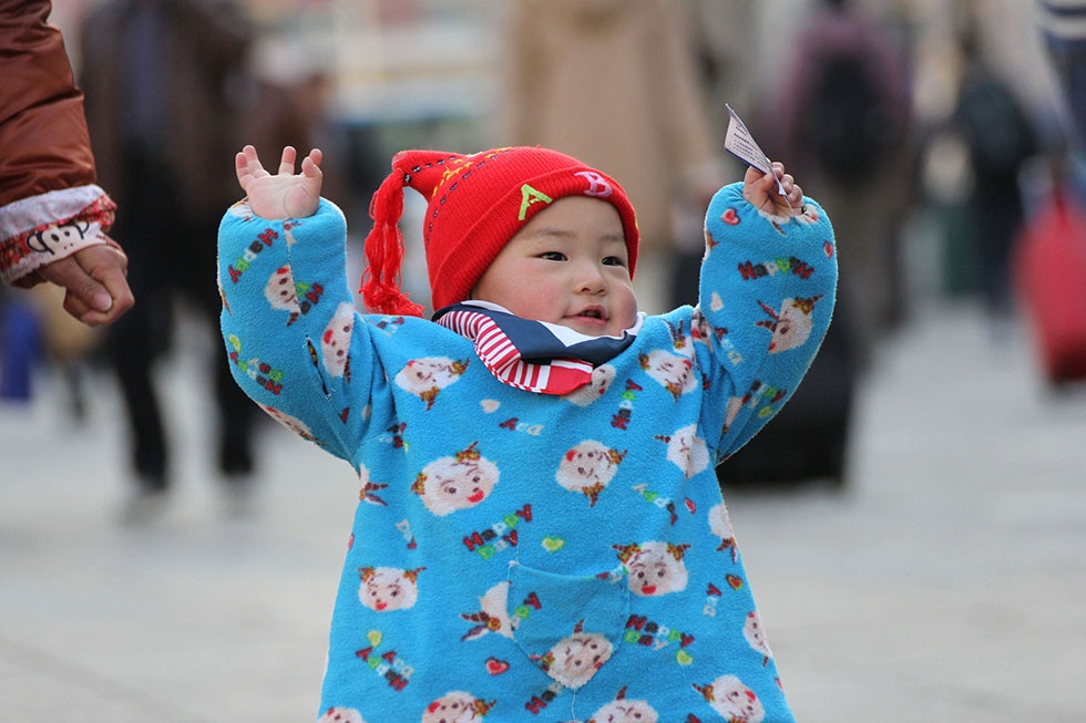 A toddler waves a train ticket, excited to be part of the world's largest human migration. (STR/AFP/Getty Images)