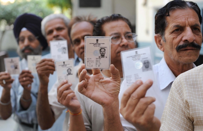 Indian voters hold up their voter ID cards as they wait to vote in Amritsar on May 13, 2009.(Narinder Nanu/AFP/Getty Images)