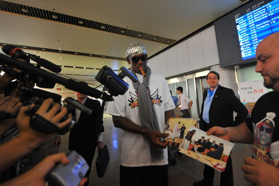 NBA Hall-of-Famer Dennis Rodman shows the press photos from his five-day trip to North Korea, including meetings with Kim Jong Un, as he arrives at Beijing International Airport from Pyongyang on September 7, 2013. (Wang Zhao/AFP/Getty Images)